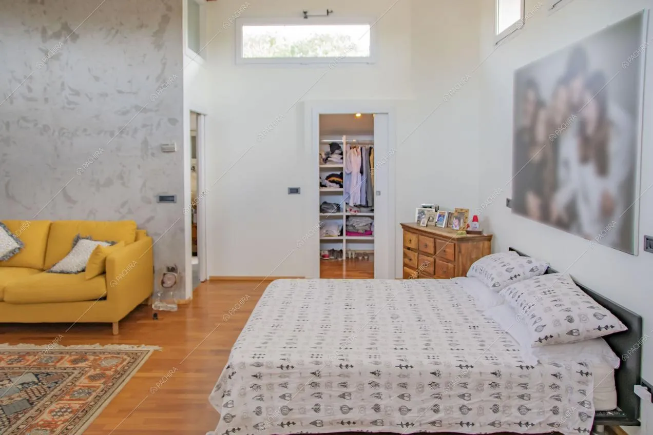 Grande camera da letto matrimoniale con pavimento in parquet e carta da parati