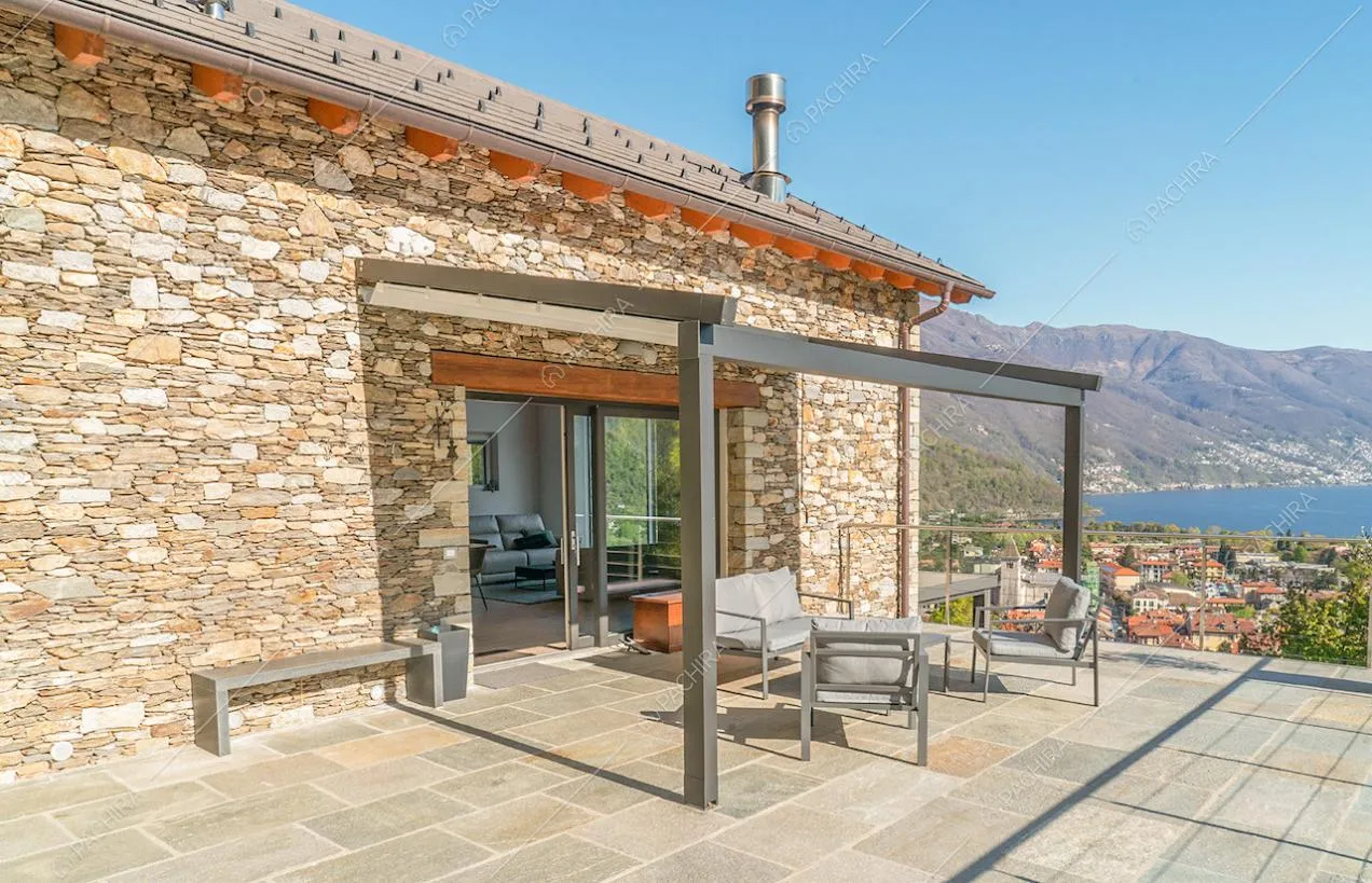 Veranda con salotto sulla terrazza con vista sugli esterni in pietra e sul lago