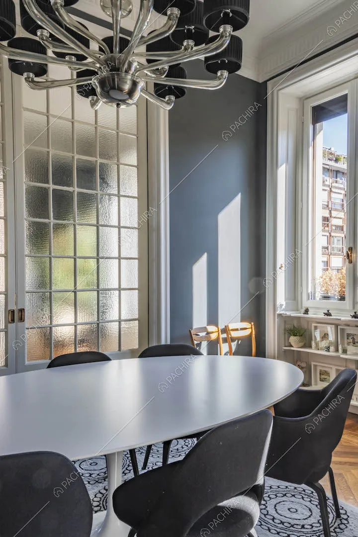 Tavolo da pranzo ovale nella sala con pareti blu e porta a vetri scorrevole