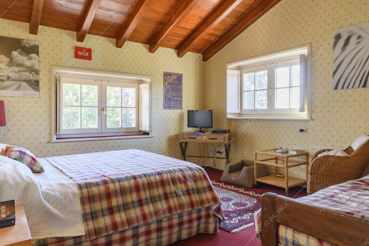 Tavolino con televisore, finestre e travi a vista nella camera da letto