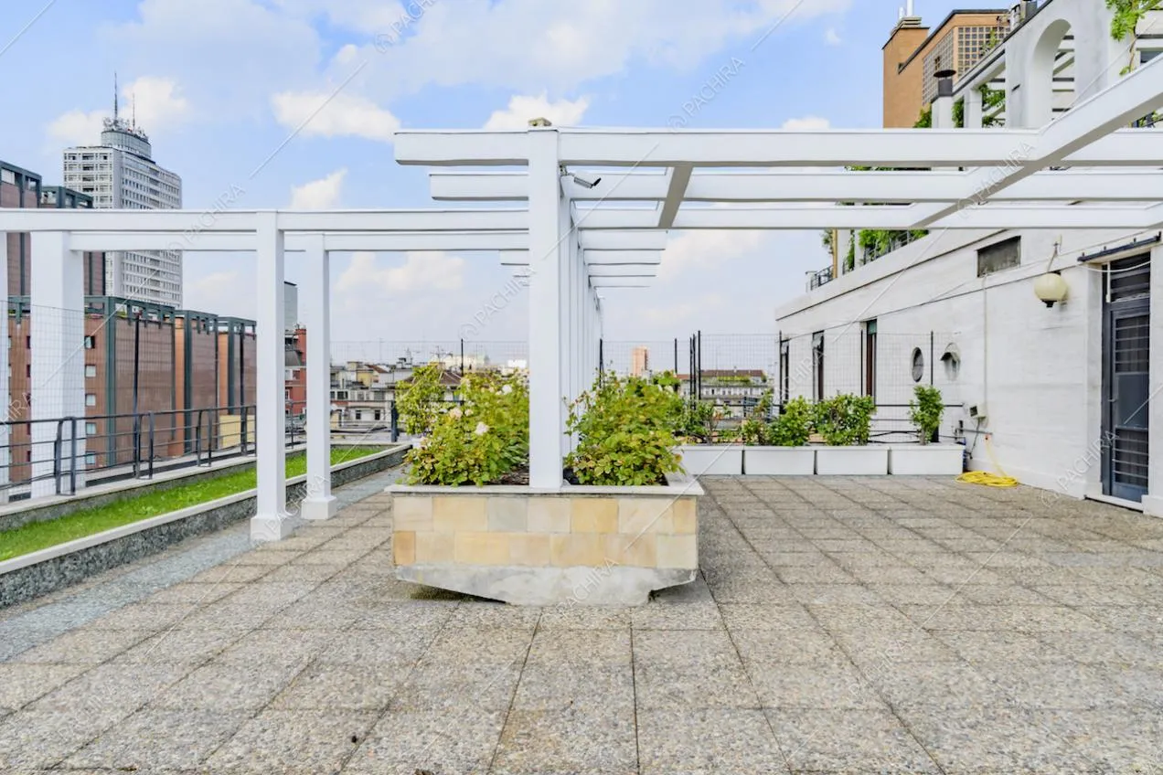 Pergolato bianco sulla terrazza con pavimentazione in pietra e vista sulla città