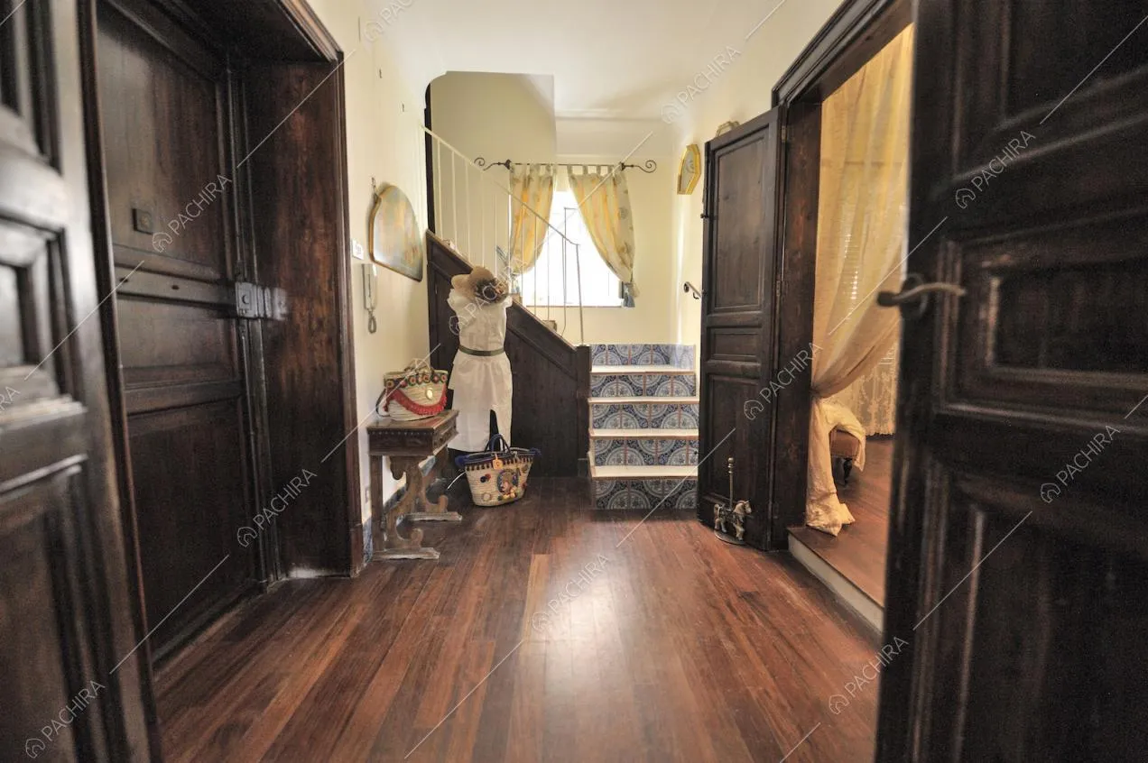 Porte in legno scuro, pavimento in parquet e tende color crema