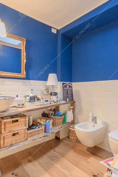 Bagno con pavimento in parquet e parete blu e in mattoncini bianchi