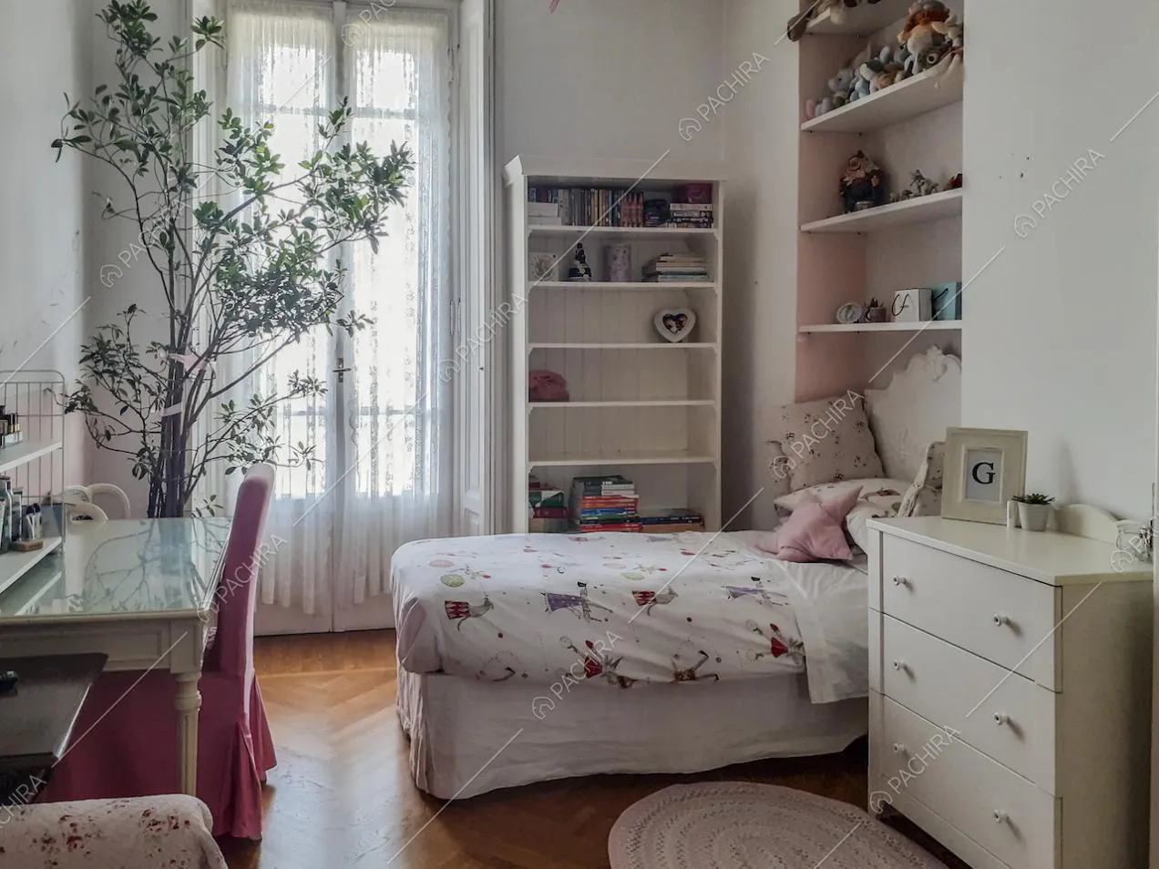 Letto singolo vicino alla cassettiera bianca e scrivania con sedia rivestita in stoffa rosa