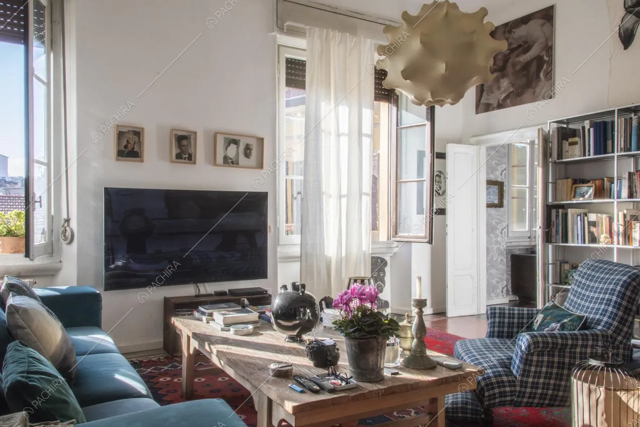 Poltrona in stoffa con fantasia a quadri, grande televisore e finestre