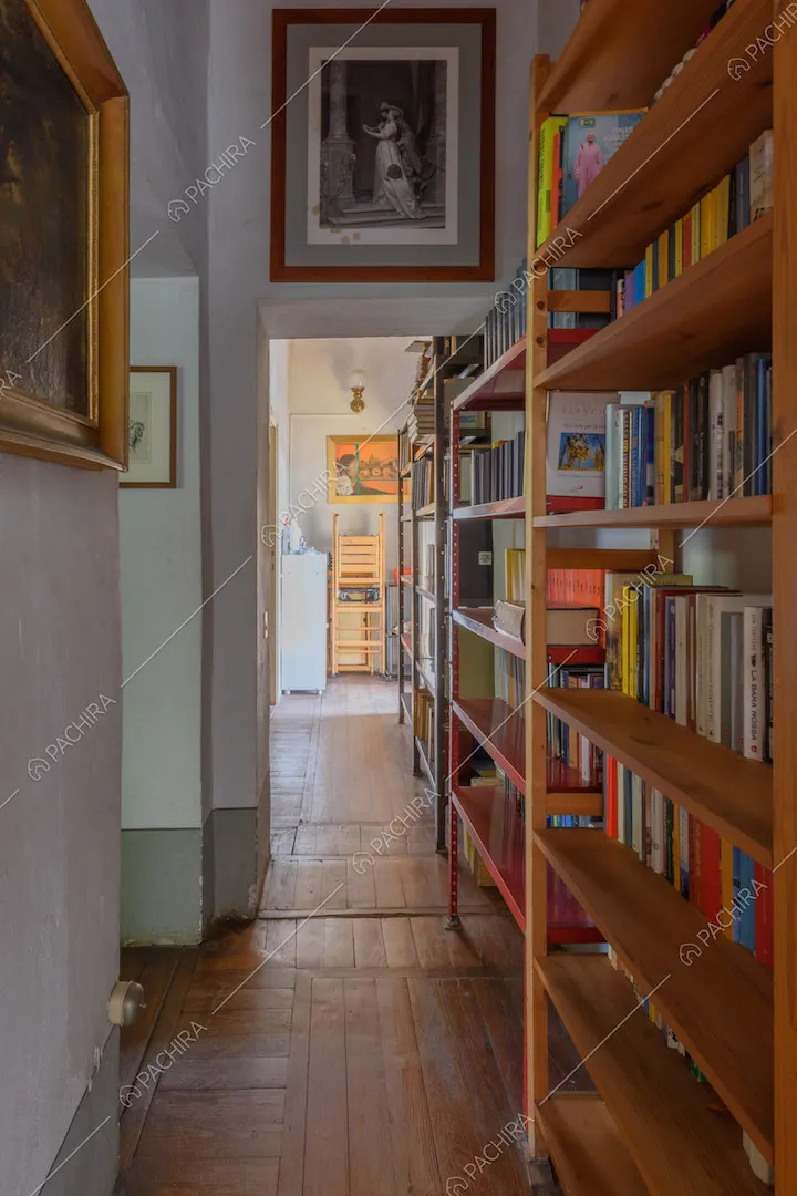 Lungo corridoio con libreria e pavimento in parquet