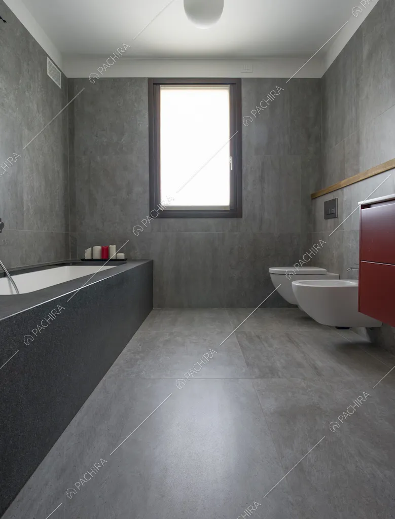 Bagno sui toni del grigio con pavimento e pareti in piastrelle e vasca da bagno