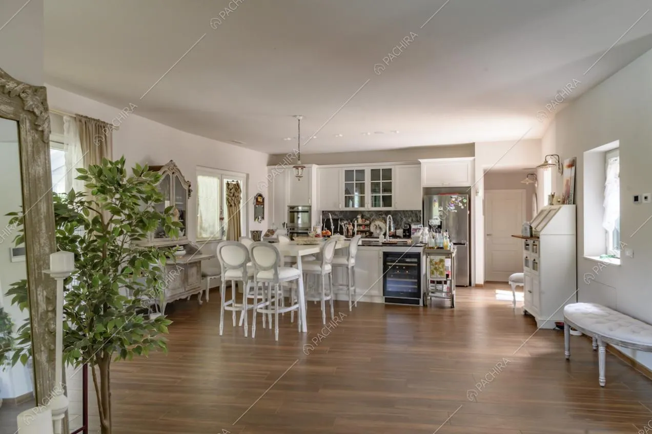 Cucina, dalle pareti bianche, a isola con lavandino, piano in marmo e bancone con sgabelli