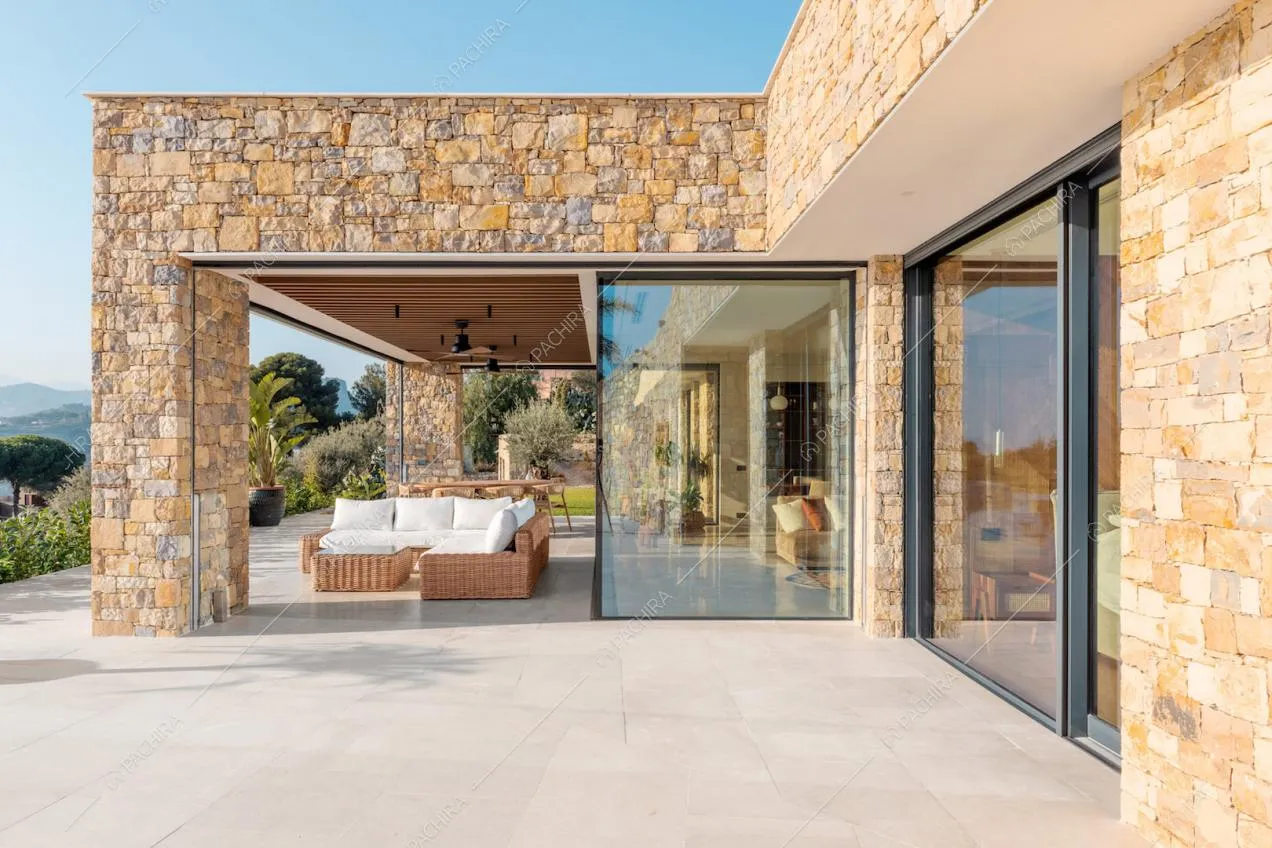 Vetrate con vista sulla zona living e veranda con divano angolare e tavolo da pranzo