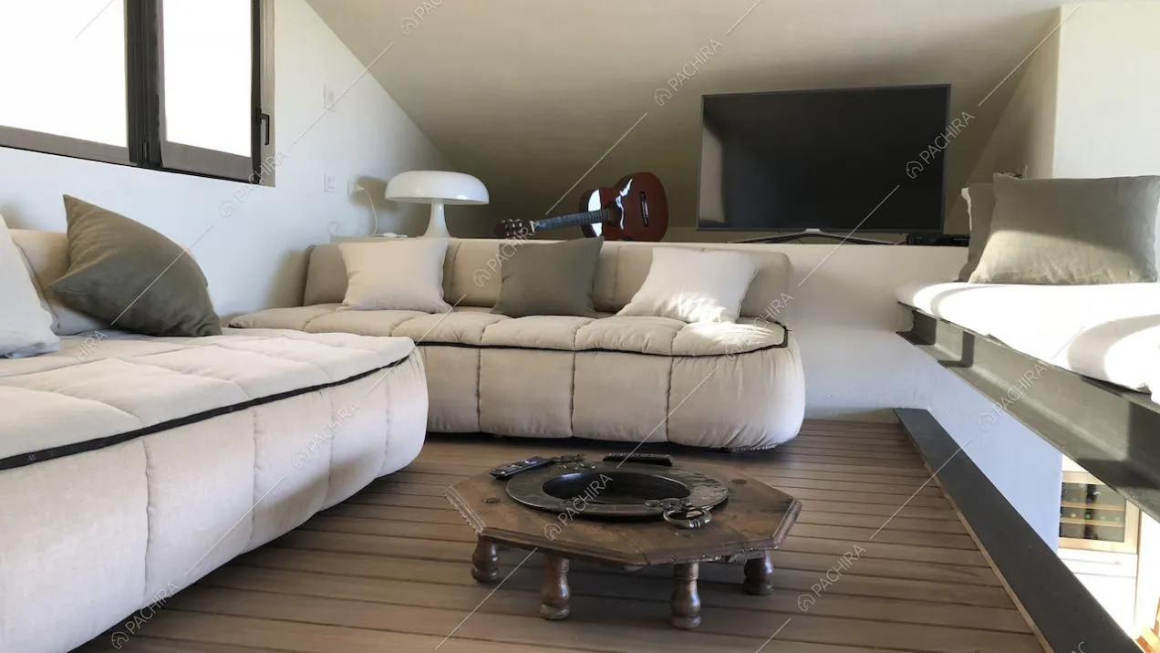 Divani con cuscini bianchi e grigi, lampada di design e televisore sul soppalco