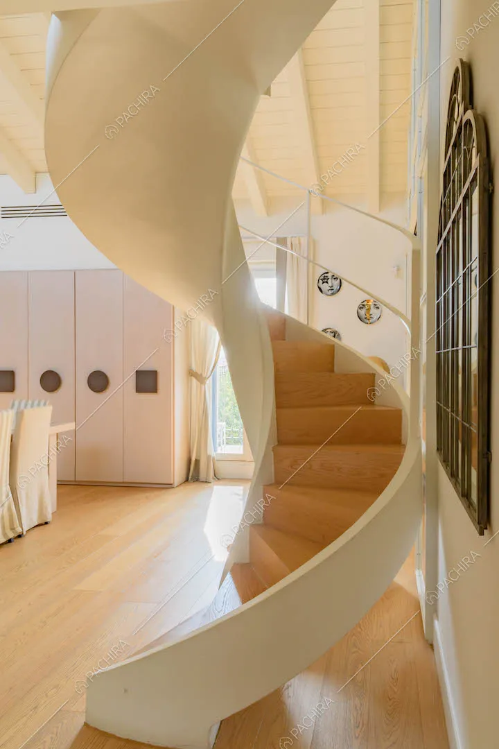 Scala bianca a chiocciola che dalla zona living conduce al piano superiore
