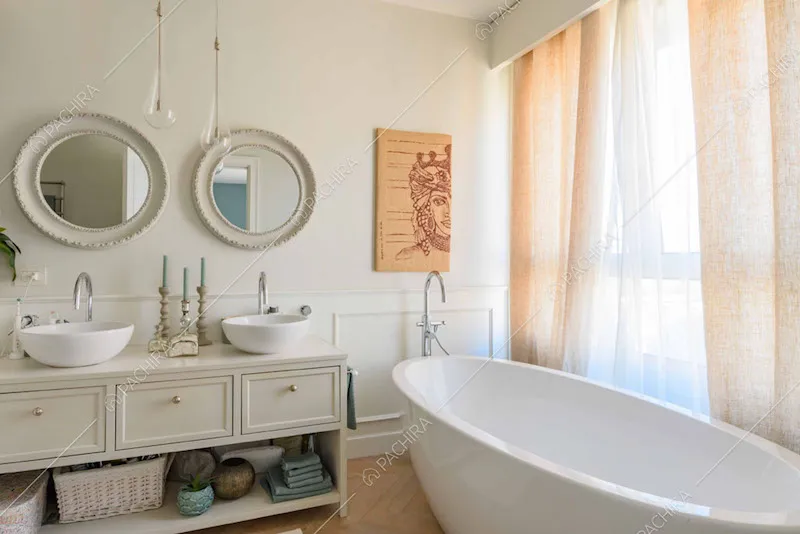 Vasca nel luminoso bagno con doppio lavandino e boiserie sulla parete