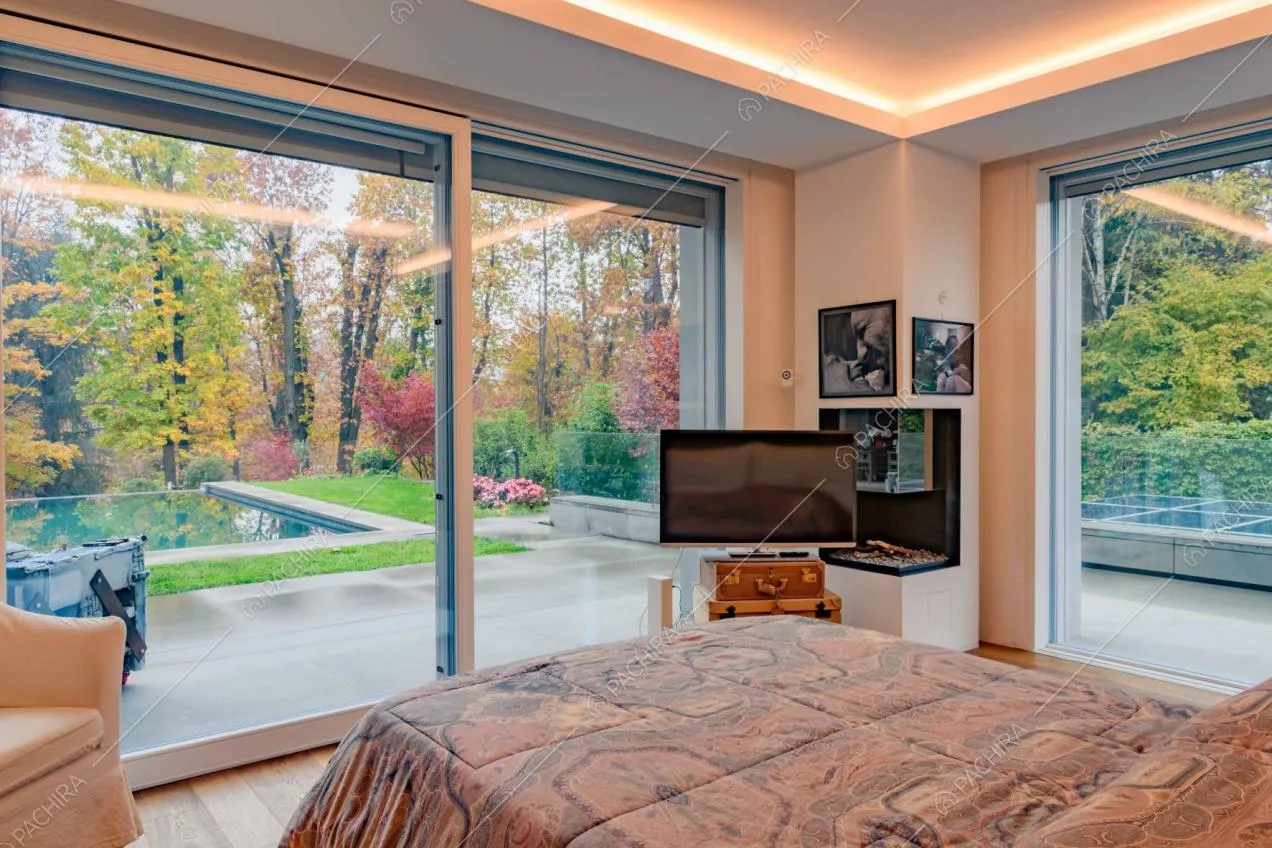 Camera da letto matrimoniale con pavimento in parquet, porte-finestre e vista sulla piscina