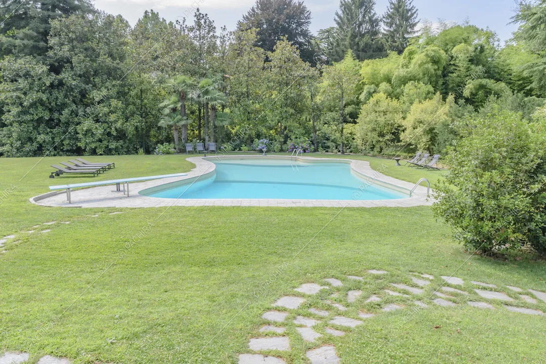 Piscina con trampolino e sedie a sdraio nel giardino della villa