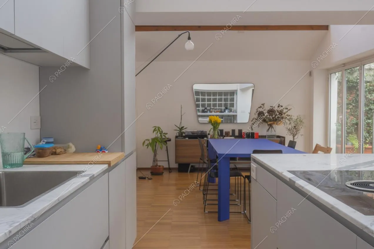 Mobili grigio chiaro per la cucina a vista e zona pranzo con tavolo blu