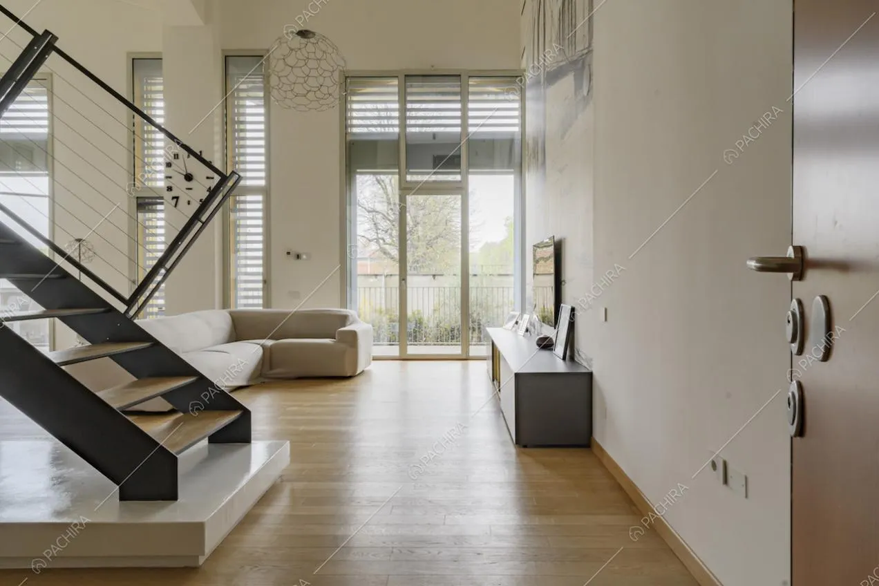 Dalla porta d'ingresso, scale per accedere al soppalco e salotto con porte-finestre