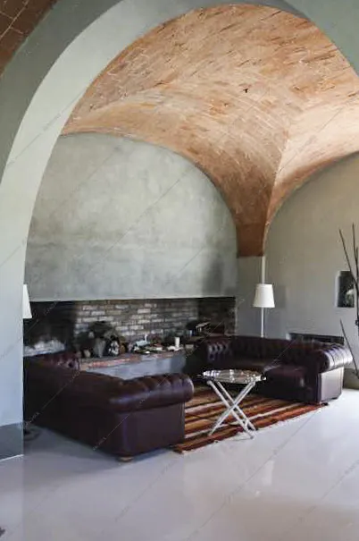 Soggiorno con divani in pelle e soffitto in mattoni
