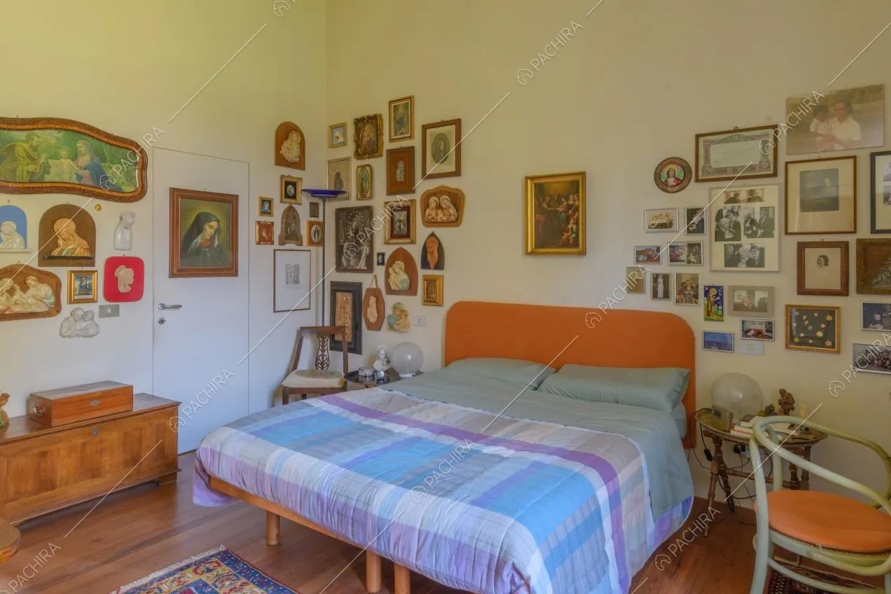 Letto matrimoniale nella luminosa camera con pavimento in parquet e pareti bianche