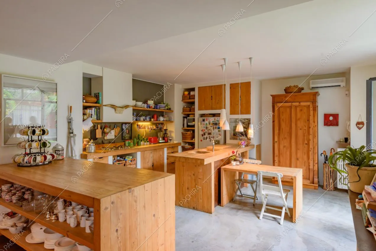 Cucina a vista con penisola in legno, fornelli a gas e pareti bianche