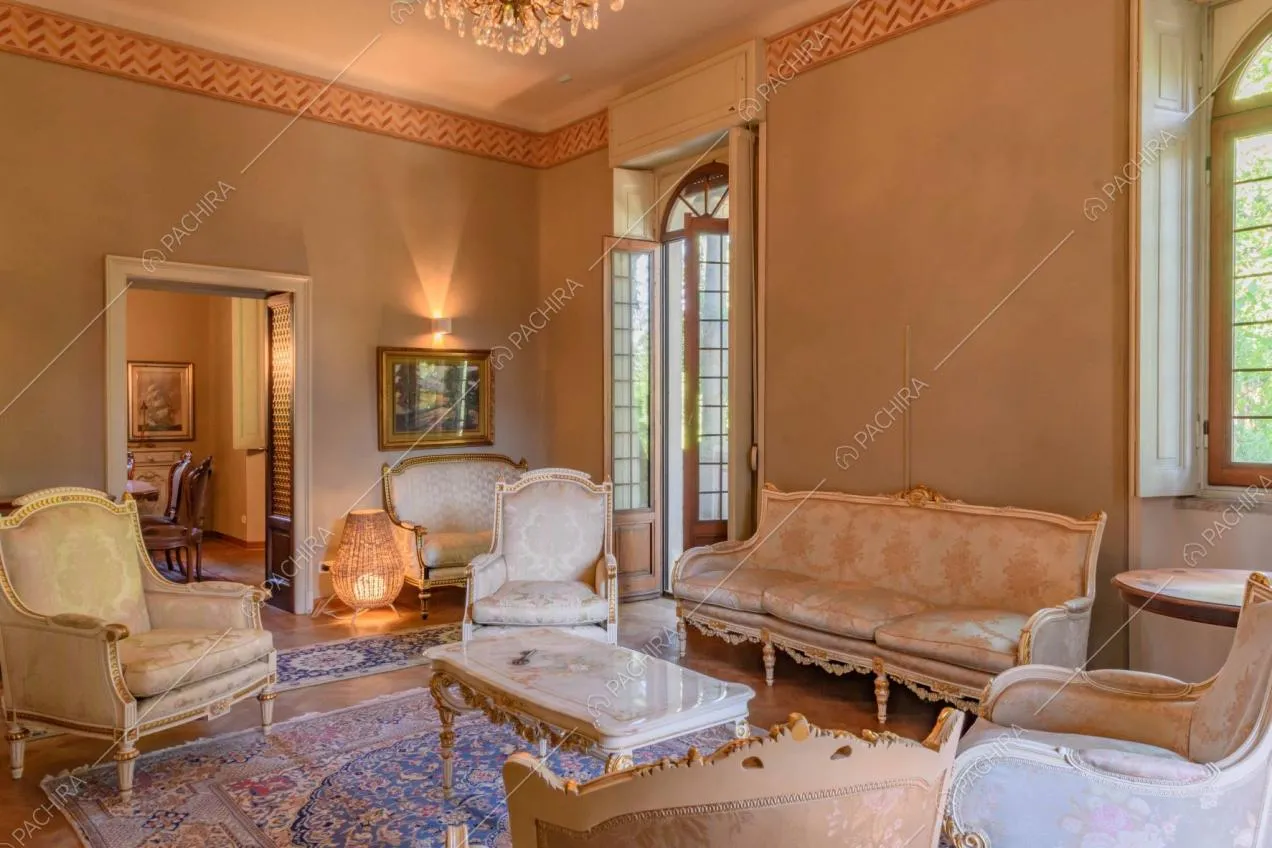 Salotto in stile classico con poltrone e divani e scorcio sulla sala da pranzo
