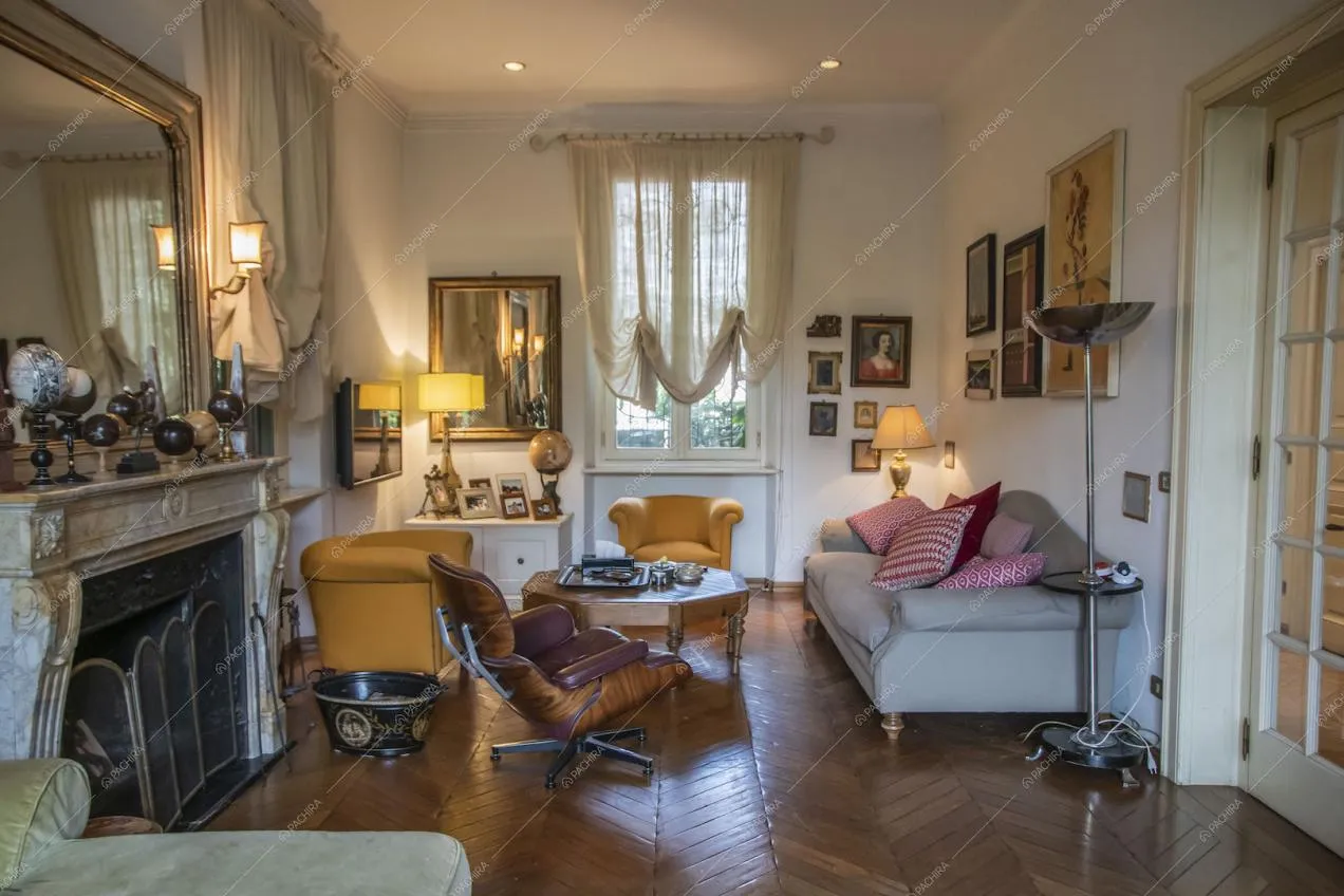 Stanza con camino, poltrone gialle, pavimento in parquet a spina di pesce e divano