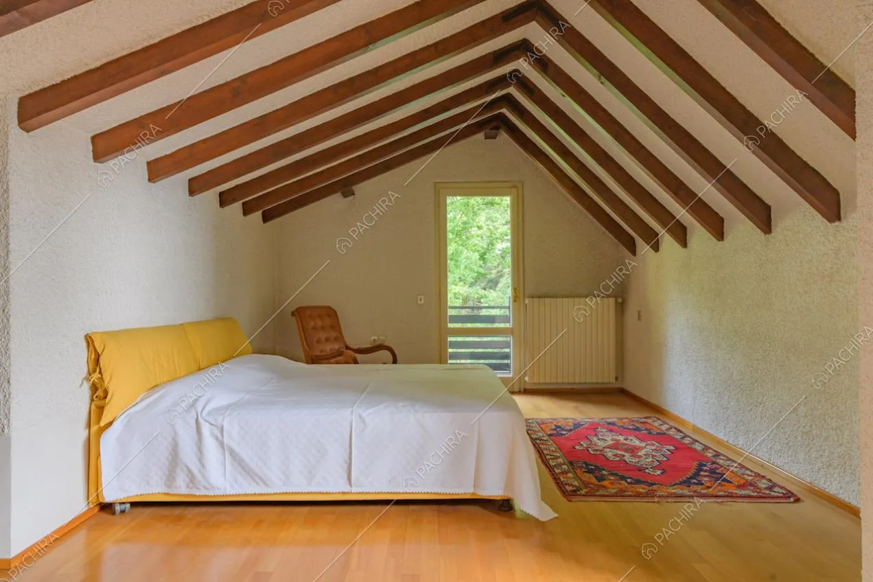 Camera da letto matrimoniale con pavimento in parquet e travi in legno sul soffitto