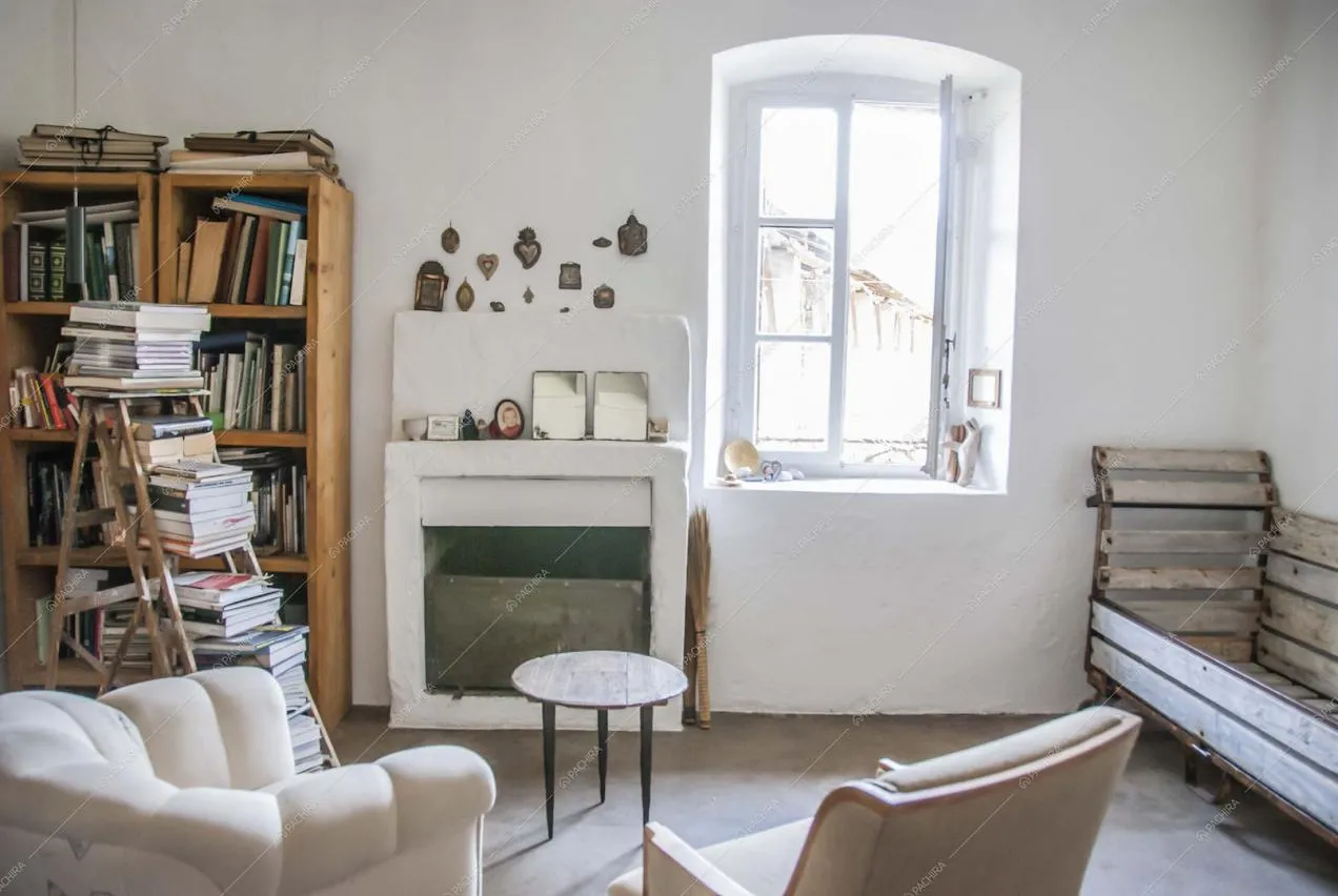 Soggiorno con poltrone, camino, scala che funge da libreria