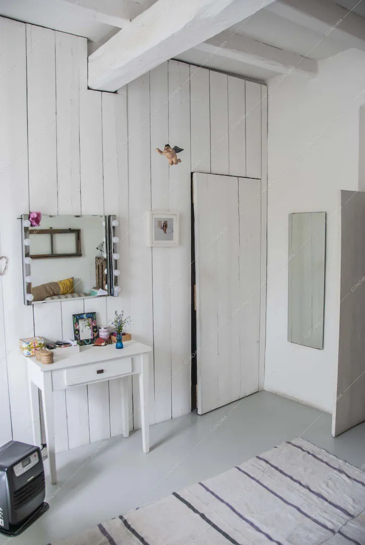 Camera con pareti in legno bianco, comodino e specchio