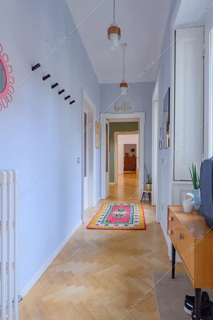 Lungo corridoio con pareti azzurre e pavimento in parquet a spina di pesce