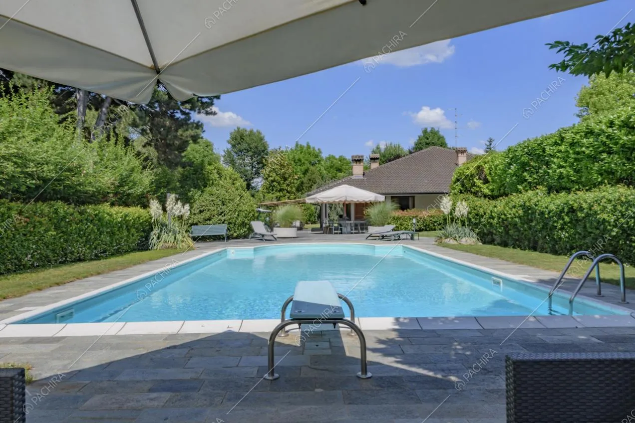 Piscina con scaletta e vista sulla villa dal giardino
