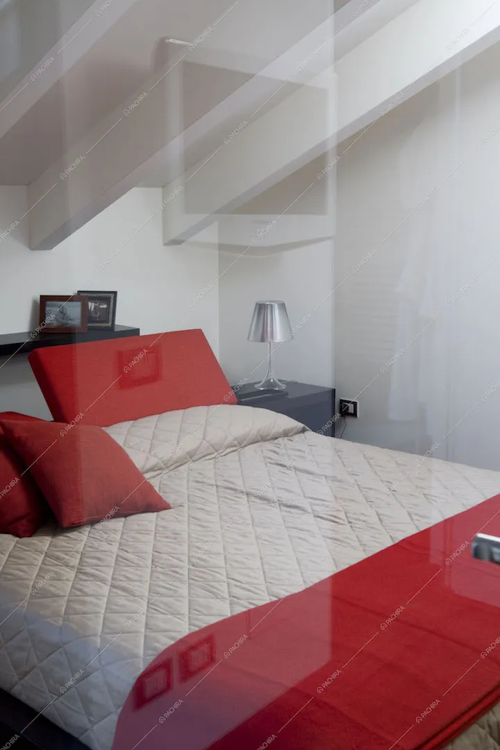 Letto a due piazze nel sottotetto, soffitto con travi a vista