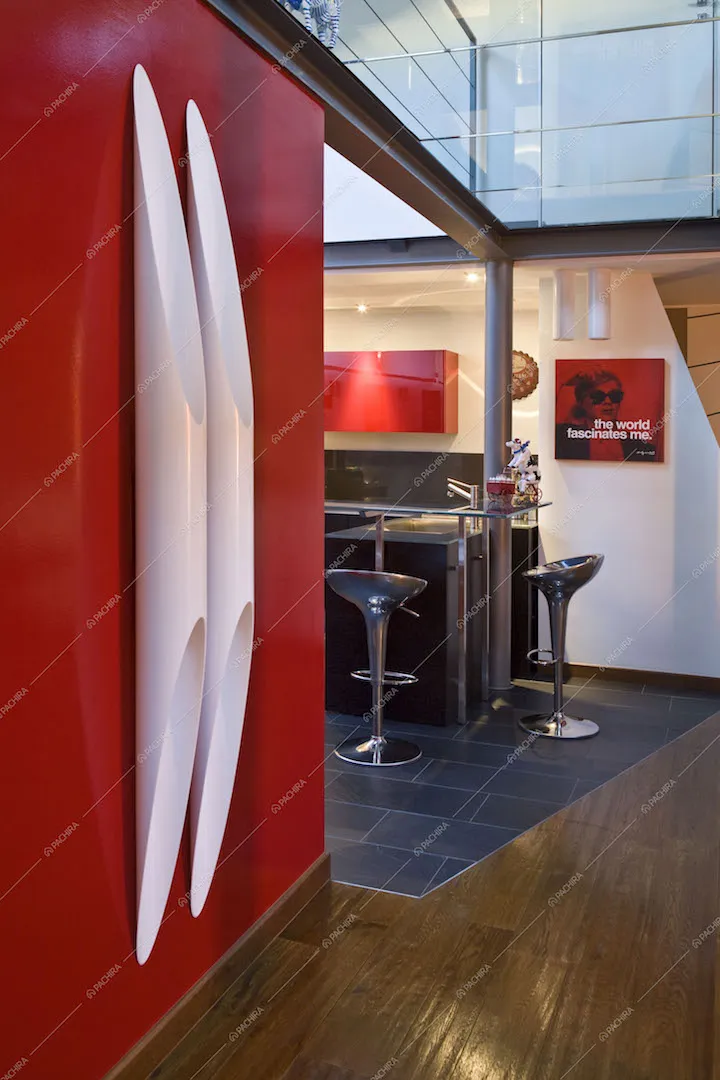 Muro rosso con sculture bianche, scorcio sulla cucina