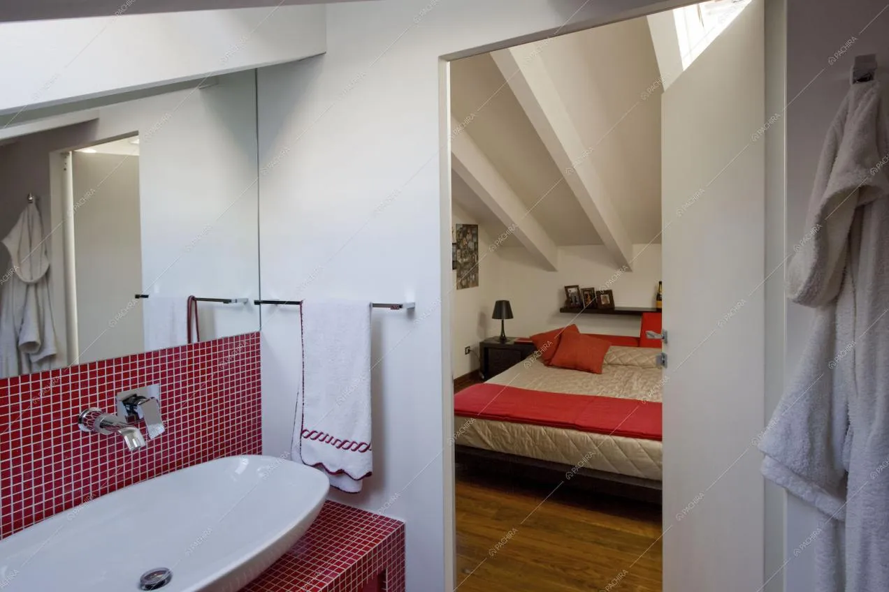 Bagno con piastrelline rosse e scorcio sulla camera da letto
