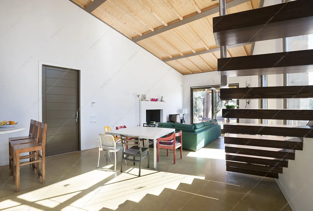 Zona living con tavolo da pranzo, porta d'ingresso e divano vista dal sottoscala