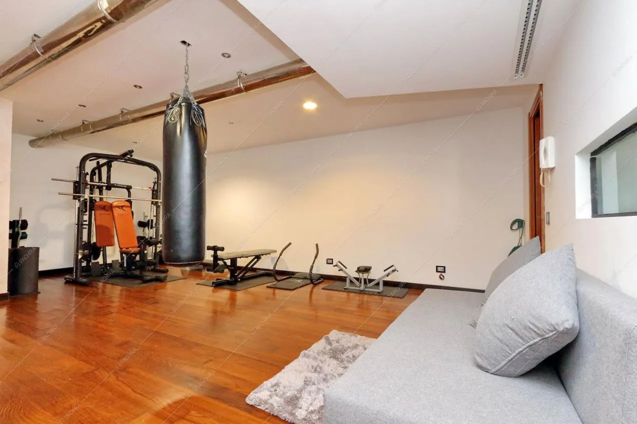 Divano e zona palestra con sacco da boxe e attrezzi