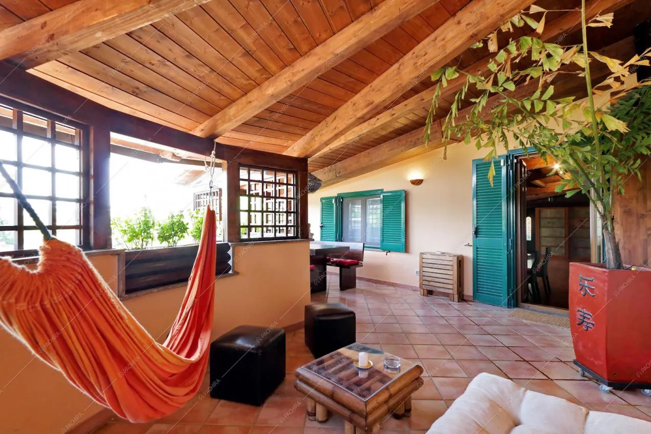 In veranda zona relax con amaca, pouf e tavolino con struttura in bambù