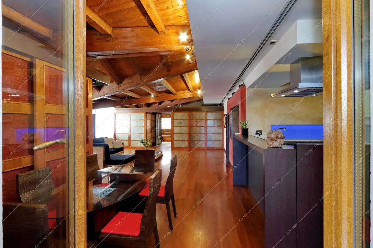 Zona pranzo con parquet a listoni e travi a vista