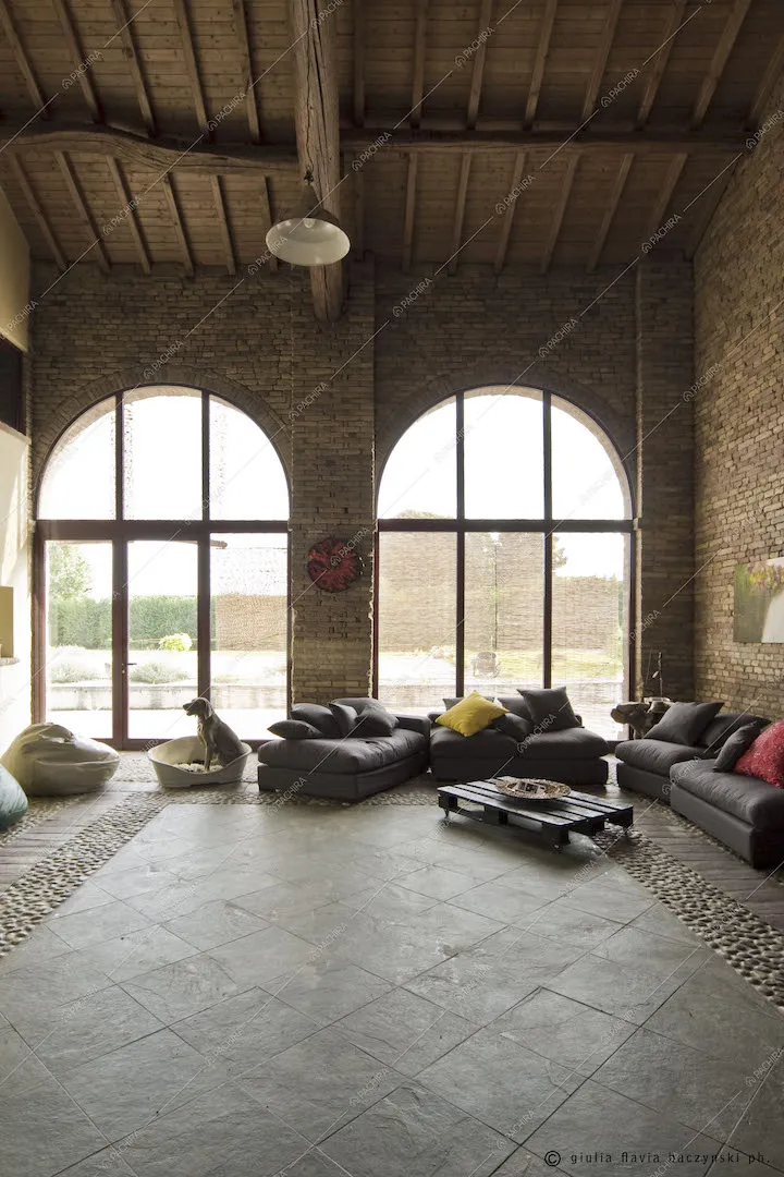 Zona living con soffitto alto, vetrate e più divani