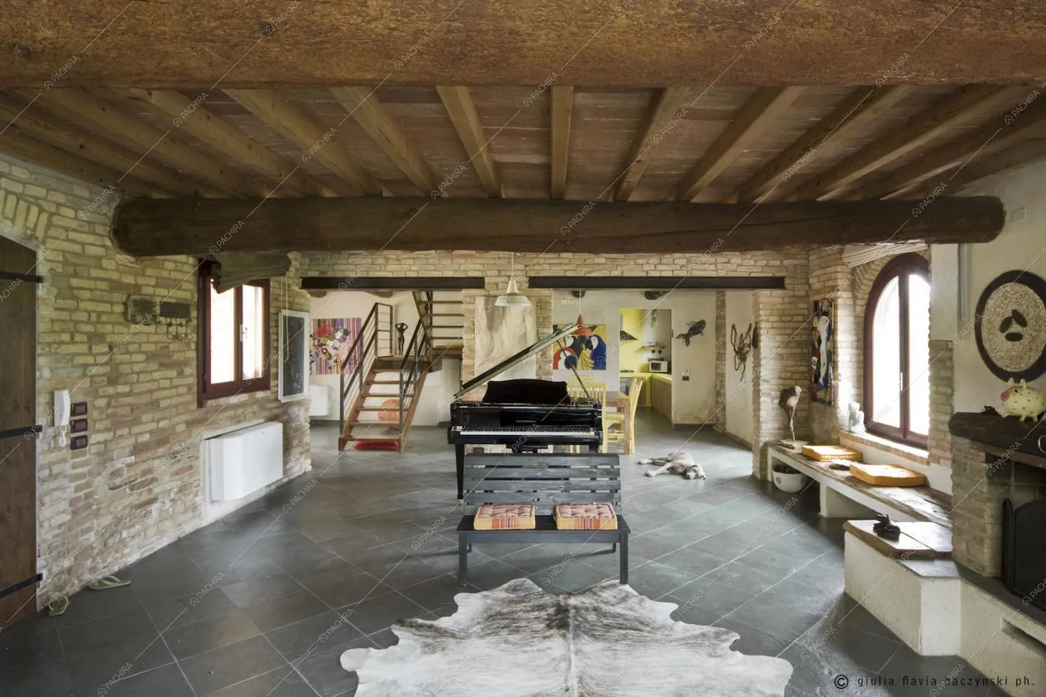 Pavimento a piastrelle, travi in legno a vista, panchina e pianoforte