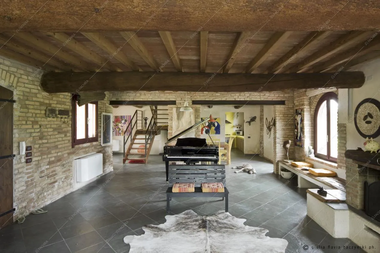 Pavimento a piastrelle, travi in legno a vista, panchina e pianoforte
