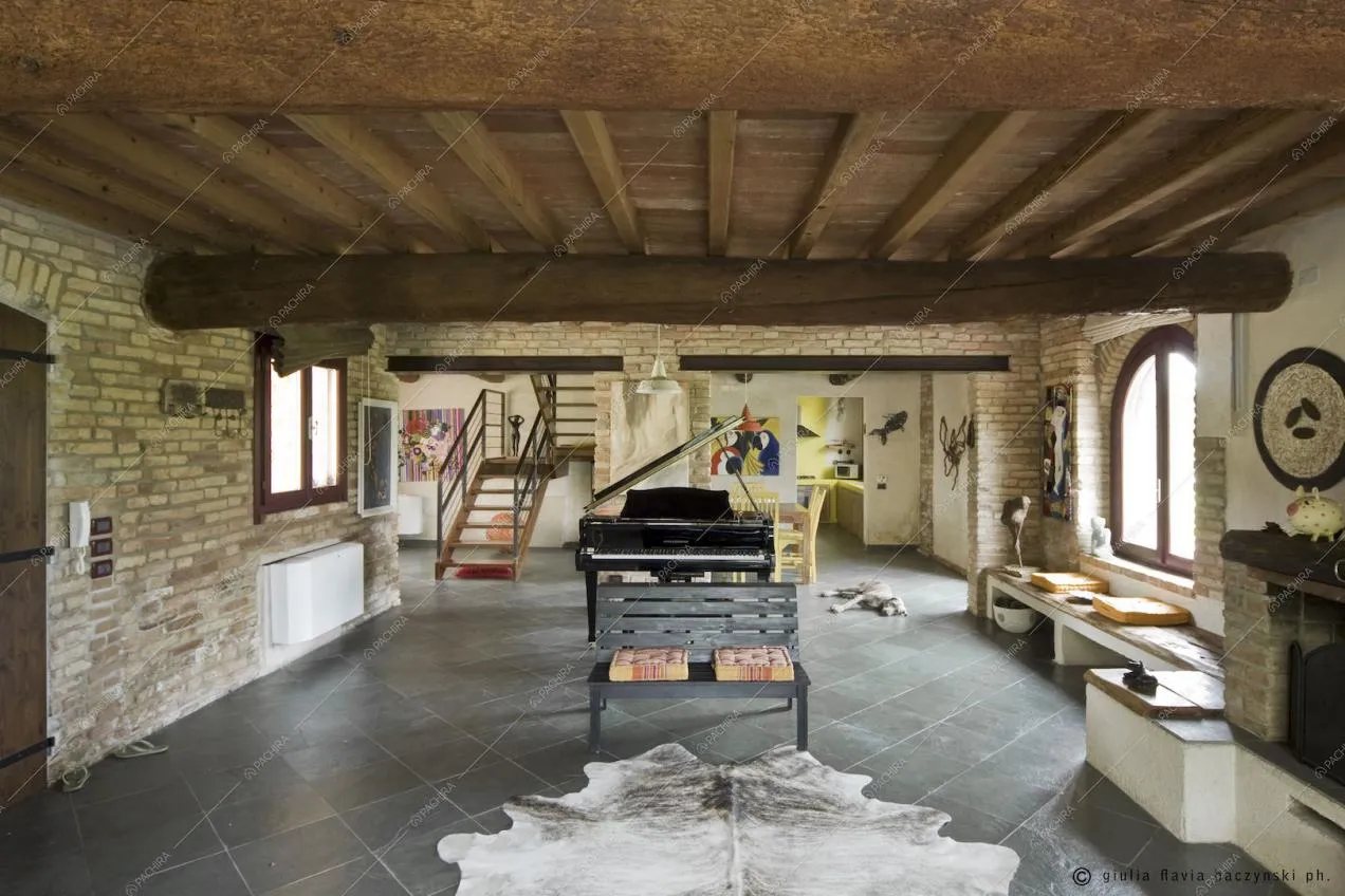 Pavimento a piastrelle, travi in legno a vista, panchina e pianoforte