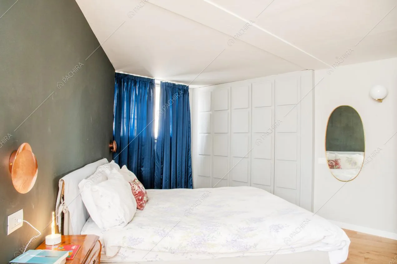 Camera da letto matrimoniale con boiserie alle pareti verde e bianca, pavimento in parquet e lampade di design