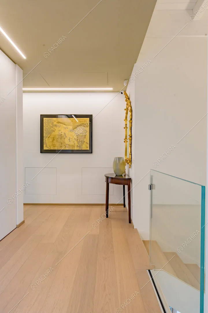 Pavimento in parquet, pareti bianche e scale con ringhiera in vetro
