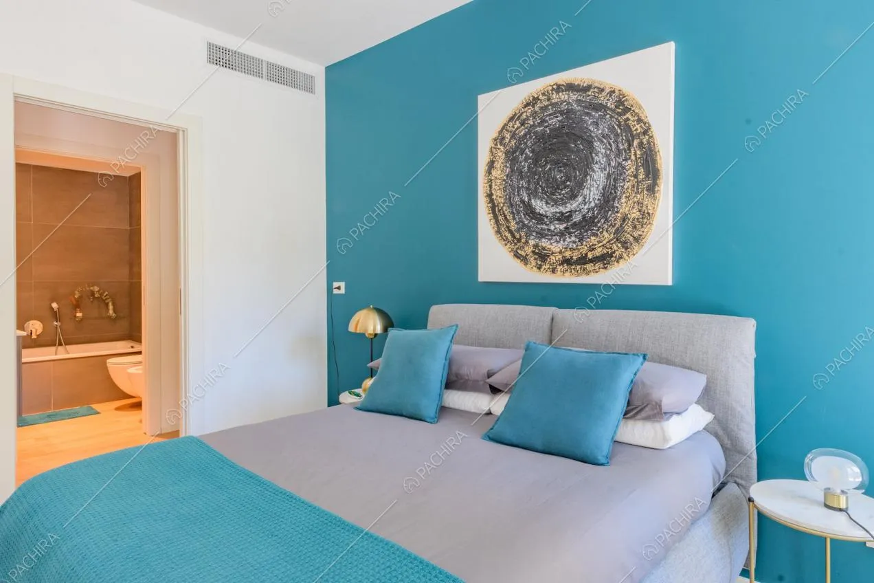 Letto matrimoniale nella luminosa camera con parete azzurra e bagno privato