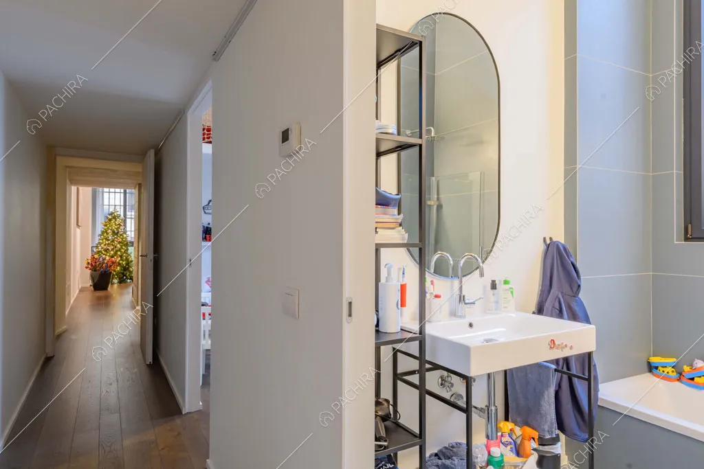 Dal corridoio con pareti bianche e pavimento in parquet vista sul bagno