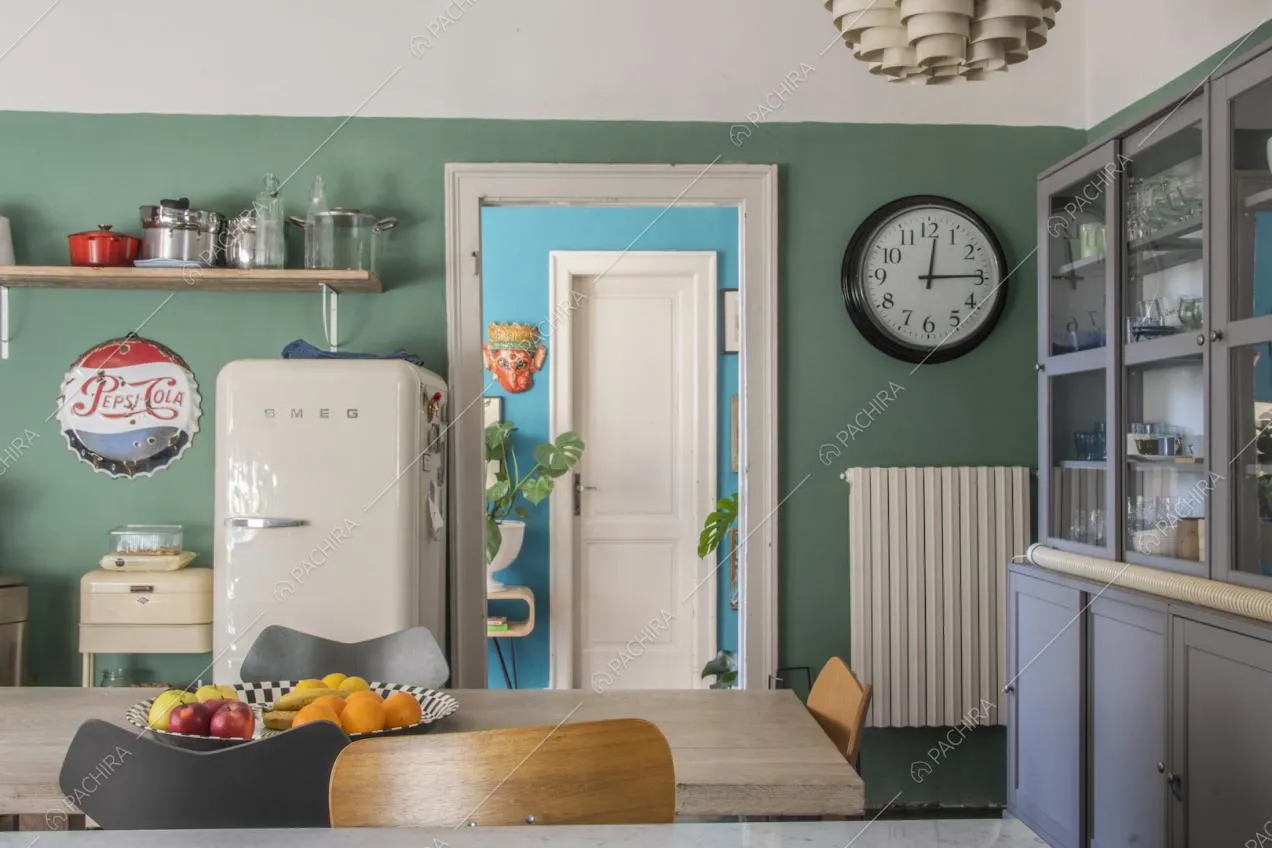 Orologio da muro e mensola di legno sulla parete verde della cucina