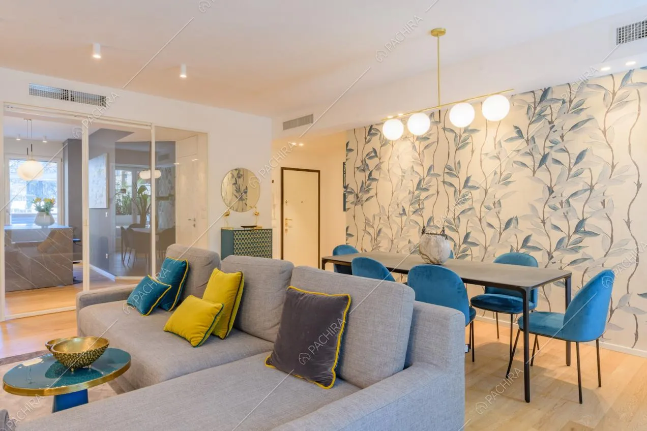 Zona living con pavimento in parquet, tavolo da pranzo e carta da parati