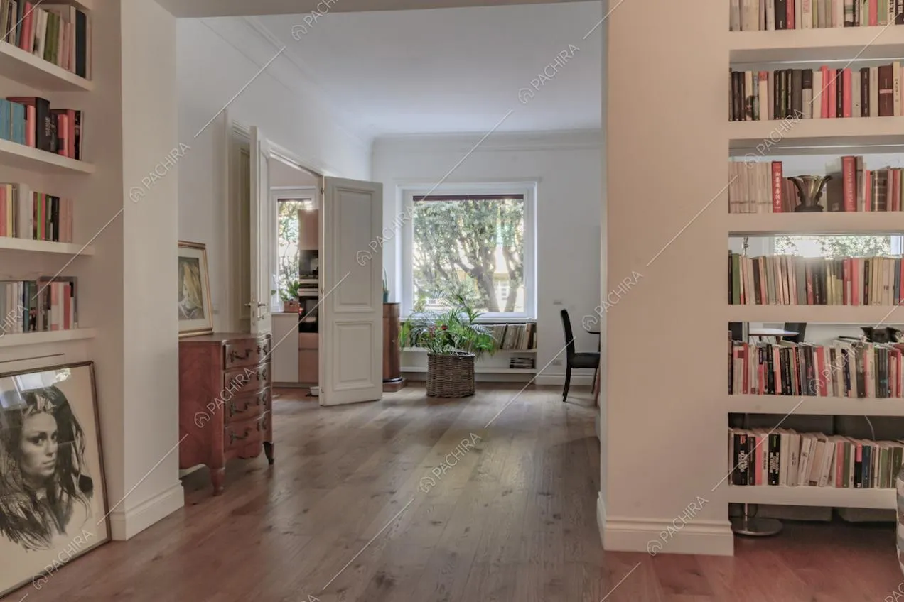 Dall'atrio con pavimento in parquet e libreria scorcio sulla cucina e su un'ampia vetrata della sala