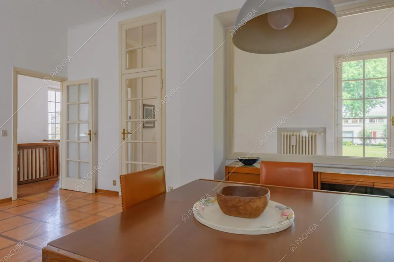 Tavolo da pranzo in legno nella zona living con pareti bianche e porte a vetri