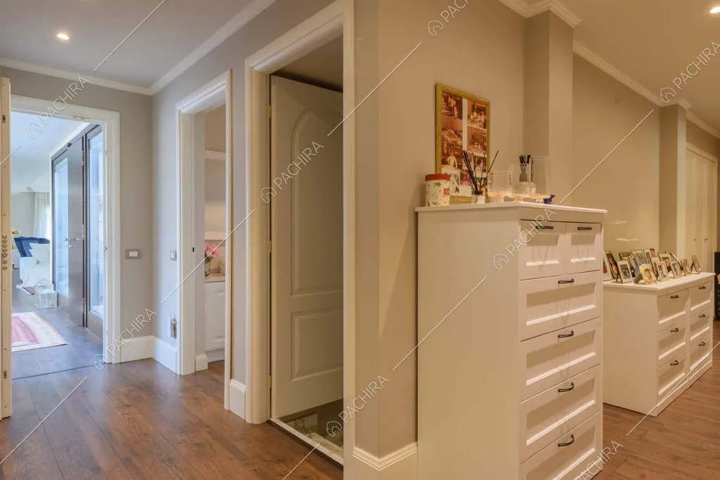 Corridoio con pavimento in parquet, cassettiere bianche e pareti grigie